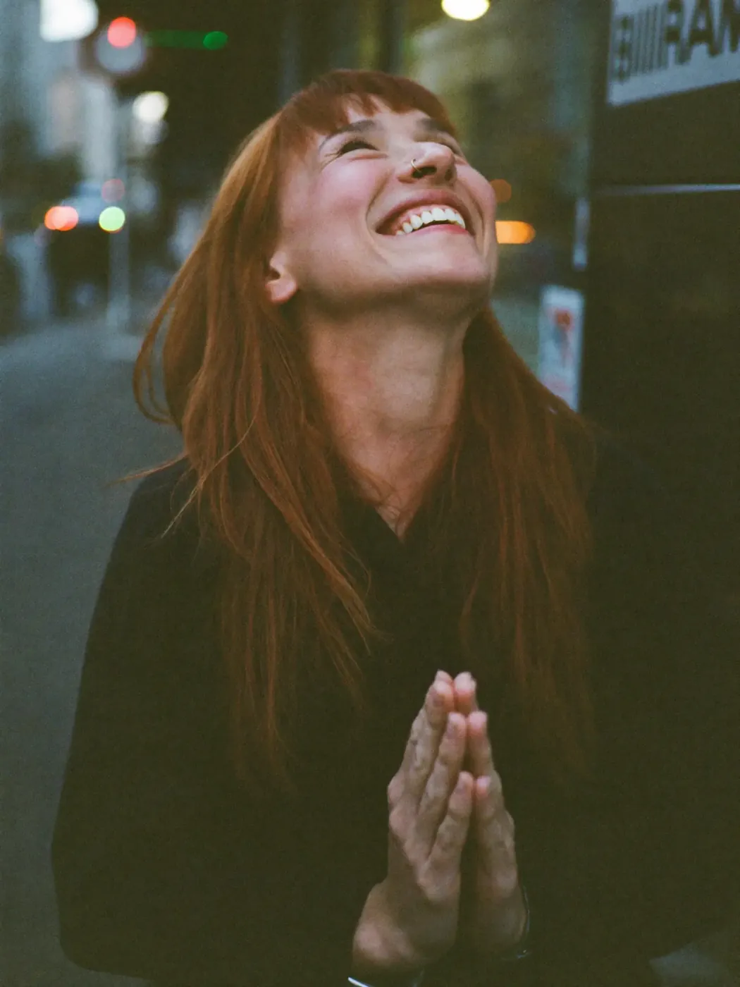 A woman laughing on a city street at dusk