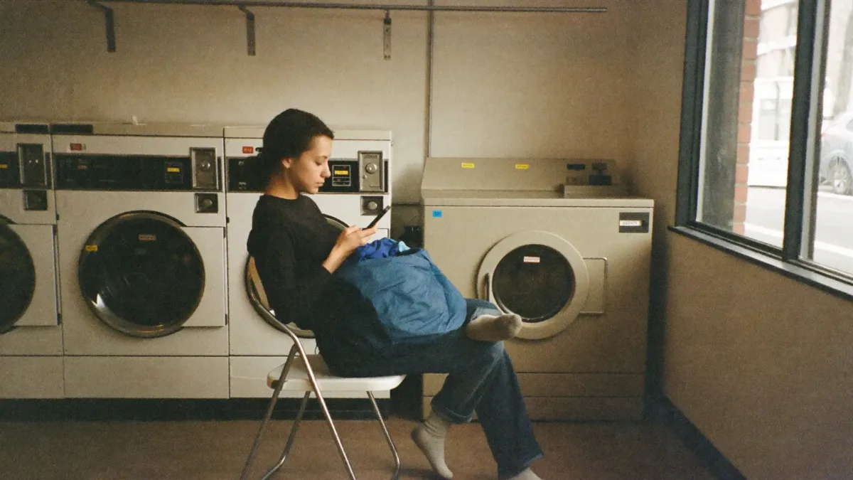A customer on her phone at a laundromat